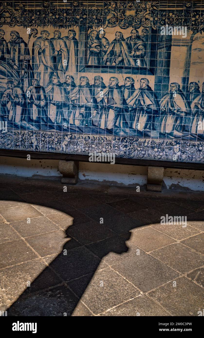 Medieval ornamented arches that generate their own shadow and silhouette and the blue azulejo panels that cover the walls of the cloister of the Cathe Stock Photo