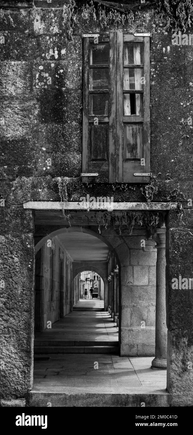 Old green wooden window and below street passage through columns of the old town of Pontevedra
