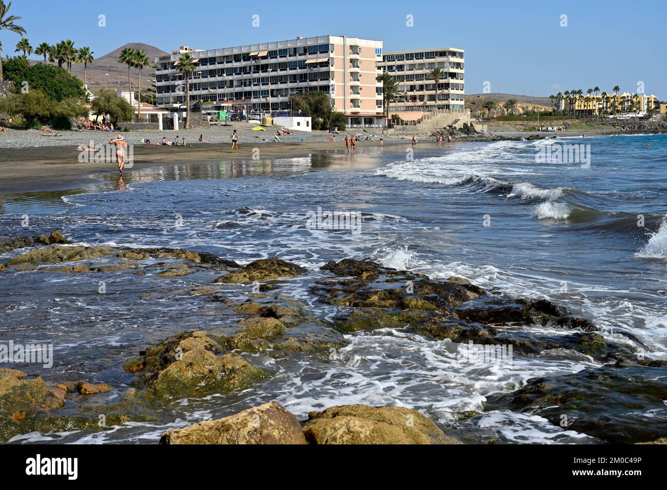 Beach with some rocky foreshore and hotel apartments of Playa del