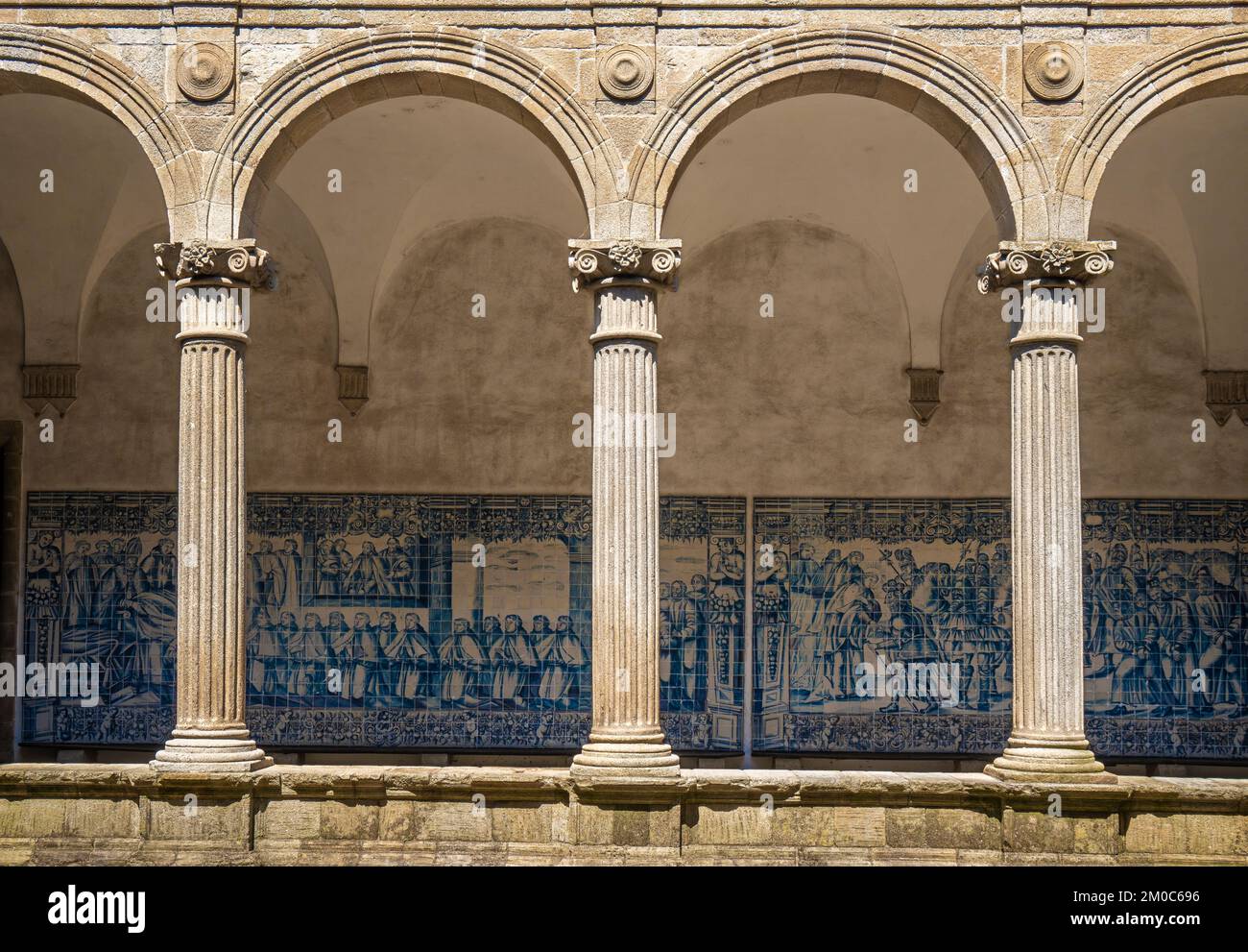 Medieval ornamented arches and behind the blue tile panels that cover the walls of the cloister of the Cathedral of Santa María de la Asunción in Vise Stock Photo