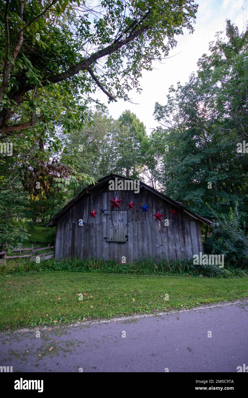 A vertical shot of a wooden cabin next to a road in the woods Stock ...