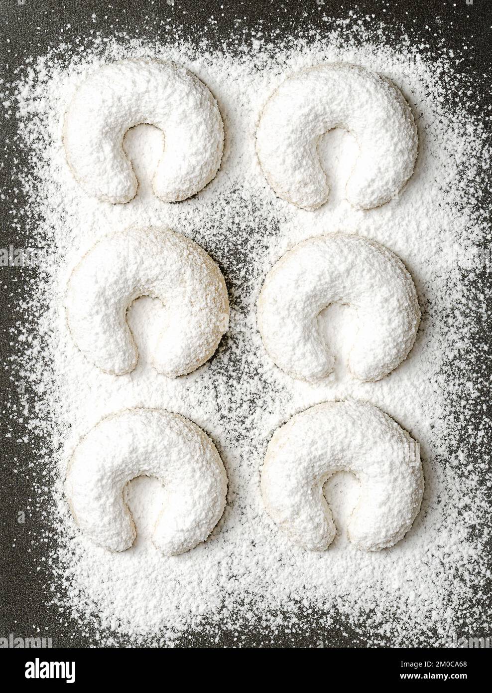 With vanilla sugar heavy dusted vanilla crescents, Vanillekipferl on a baking tray. Crescent shaped Christmas biscuits, originally from Austria. Stock Photo