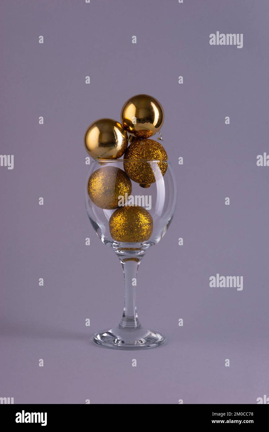 golden christmas tree balls in a wine glass on a gray background Stock Photo
