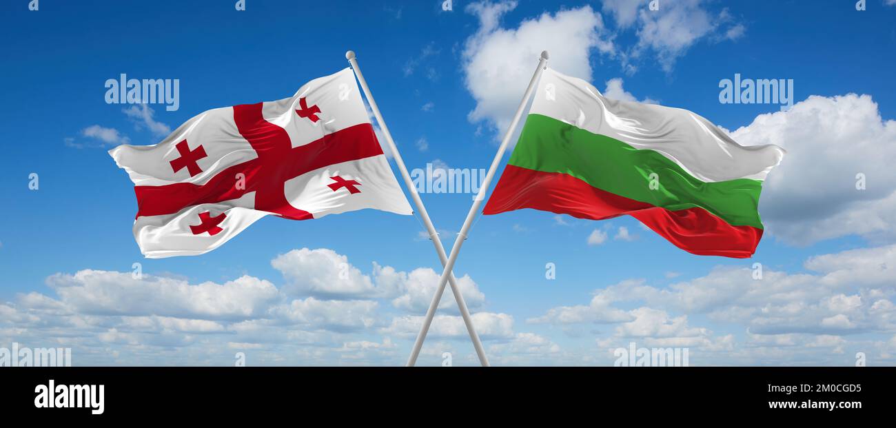 two crossed flags Bulgaria and Georgia waving in wind at cloudy sky ...