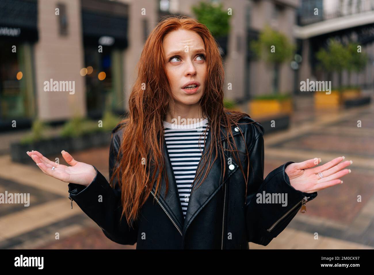 Portrait of upset pretty young woman with long red-hair standing with ...