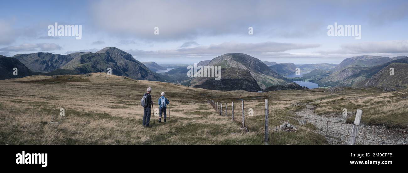 Panorama of two fell walkers enjoying the glorious views from Brandreth of Pillar, Ennerdale, Haystacks and Crummock Water Stock Photo