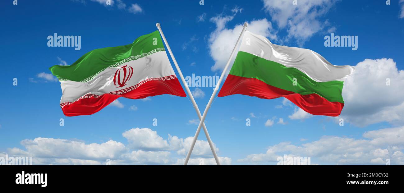 two crossed flags Bulgaria and Iran waving in wind at cloudy sky ...