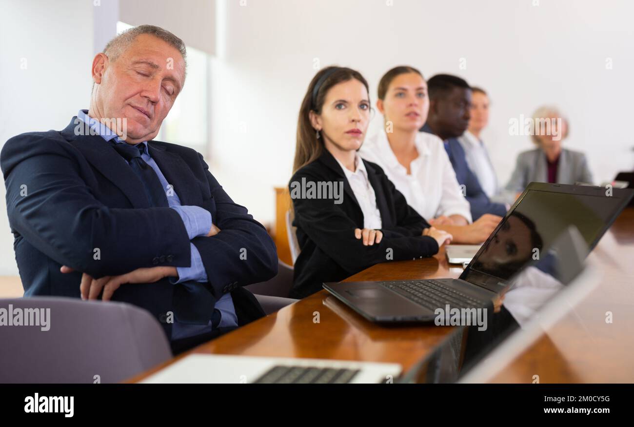 Image showcasing Man in suit sleeping during conference Stock Photo - Alamy