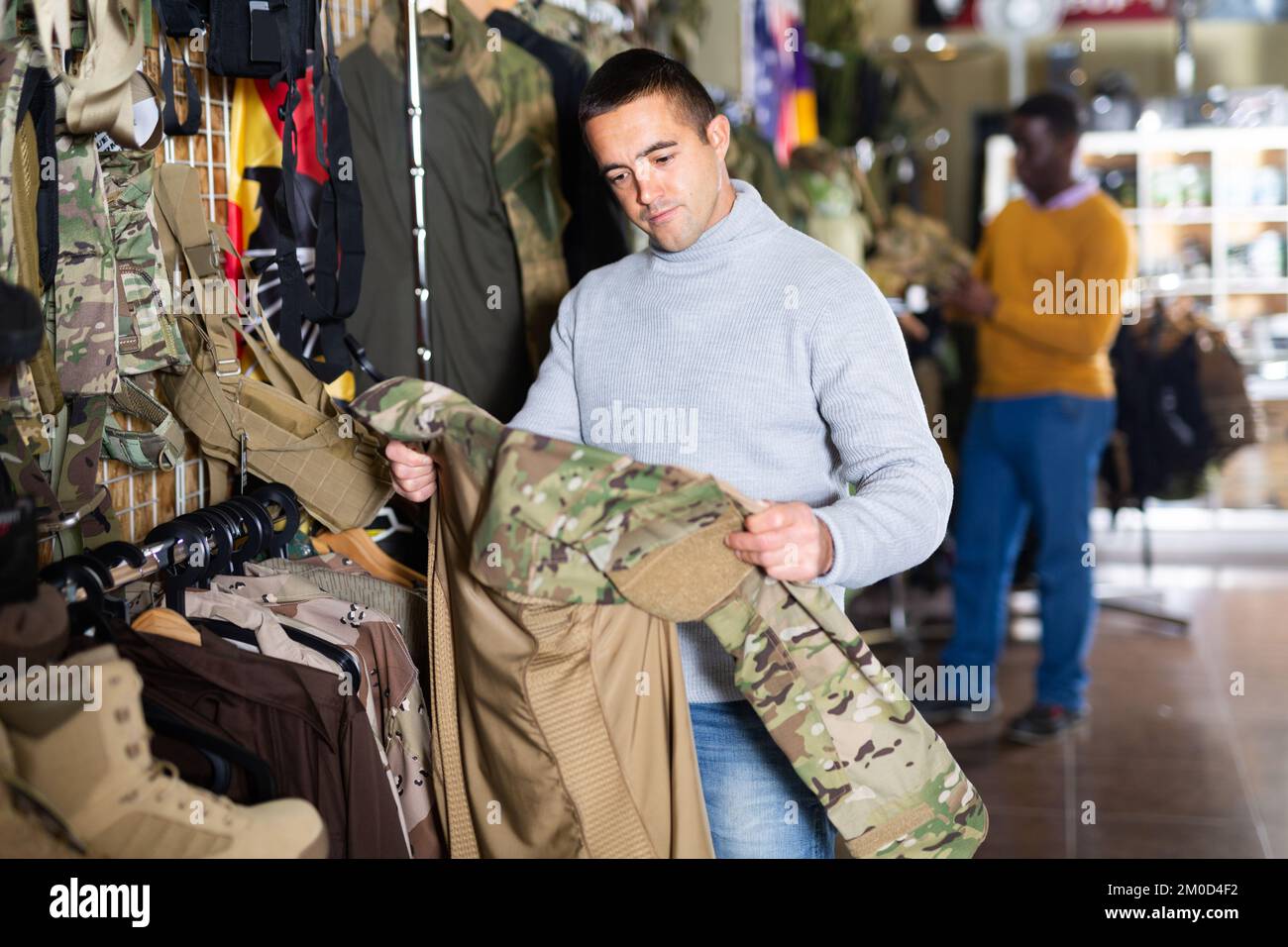 Guy choosing camouflage uniform in military shop Stock Photo Alamy