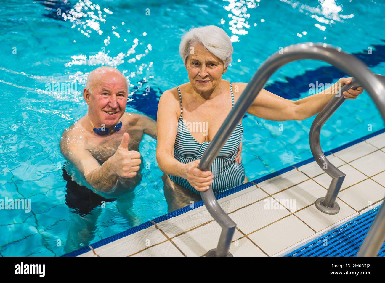Sport and active leisure time for pensioners. Two positive caucasian senior adults near a pool ladder. Senior man showing thumbs up and looking to the camera. High quality photo Stock Photo