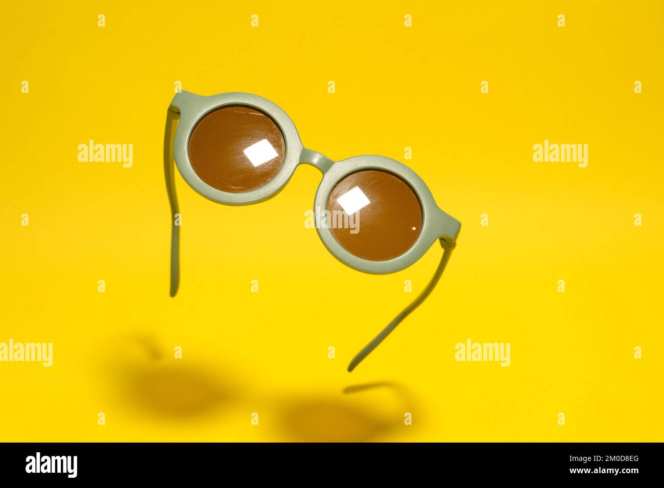 Funny round retro green sunglasses for kids on yellow background Stock Photo