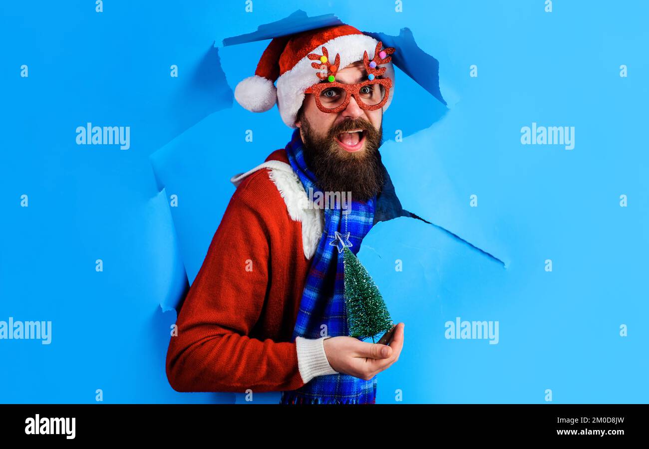 Santa Claus with small Christmas tree looking through paper hole. Discount. New year sales. Stock Photo