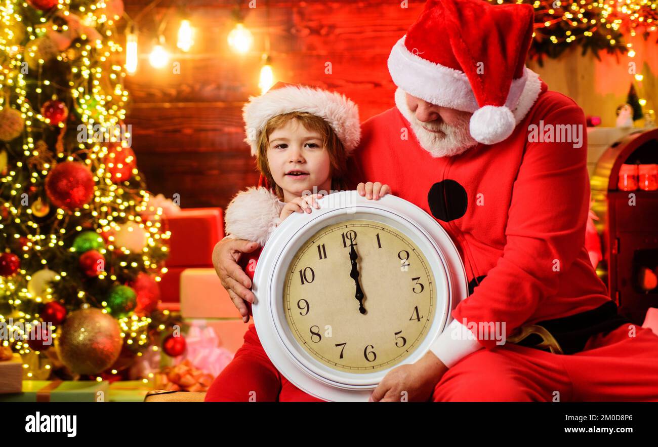Little child boy and Santa Claus with old clock. Waiting for Christmas. New year midnight. Stock Photo