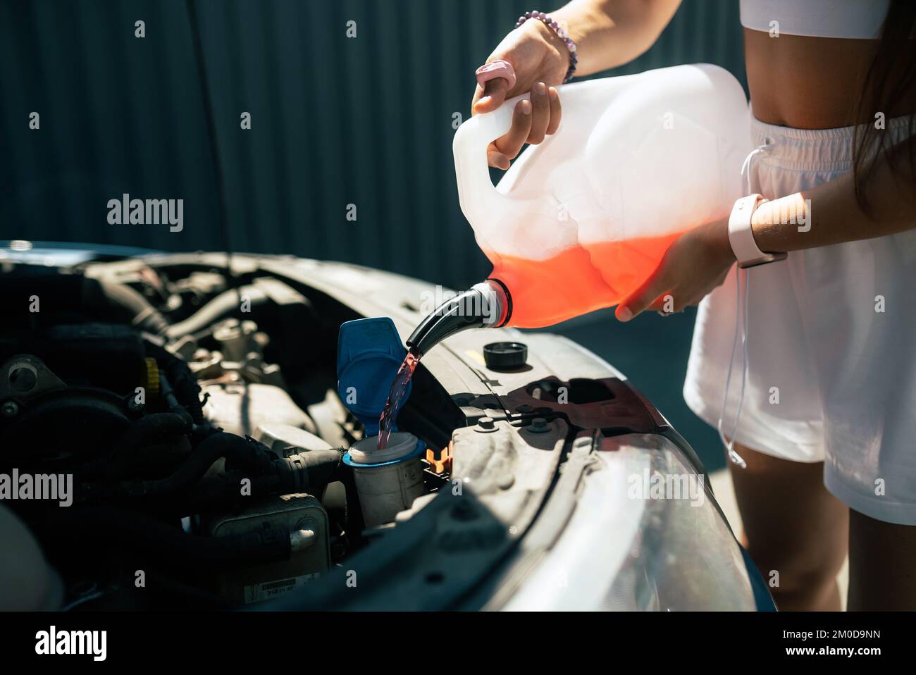 Young woman pouring antifreeze car screen wash liquid into car Stock