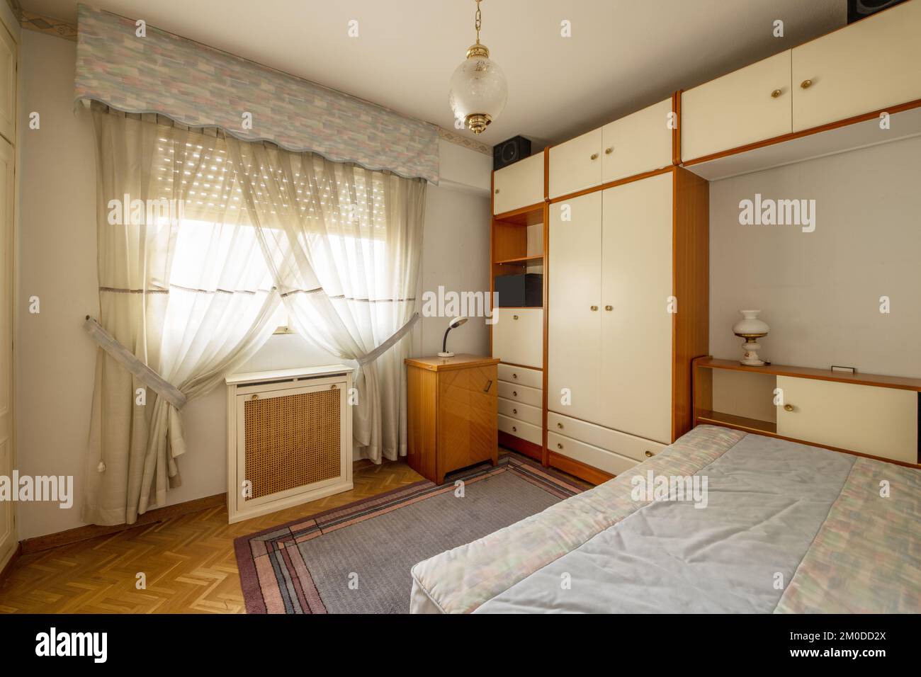 A bedroom with cherry and white wood furniture, a single bed, a mirror ...
