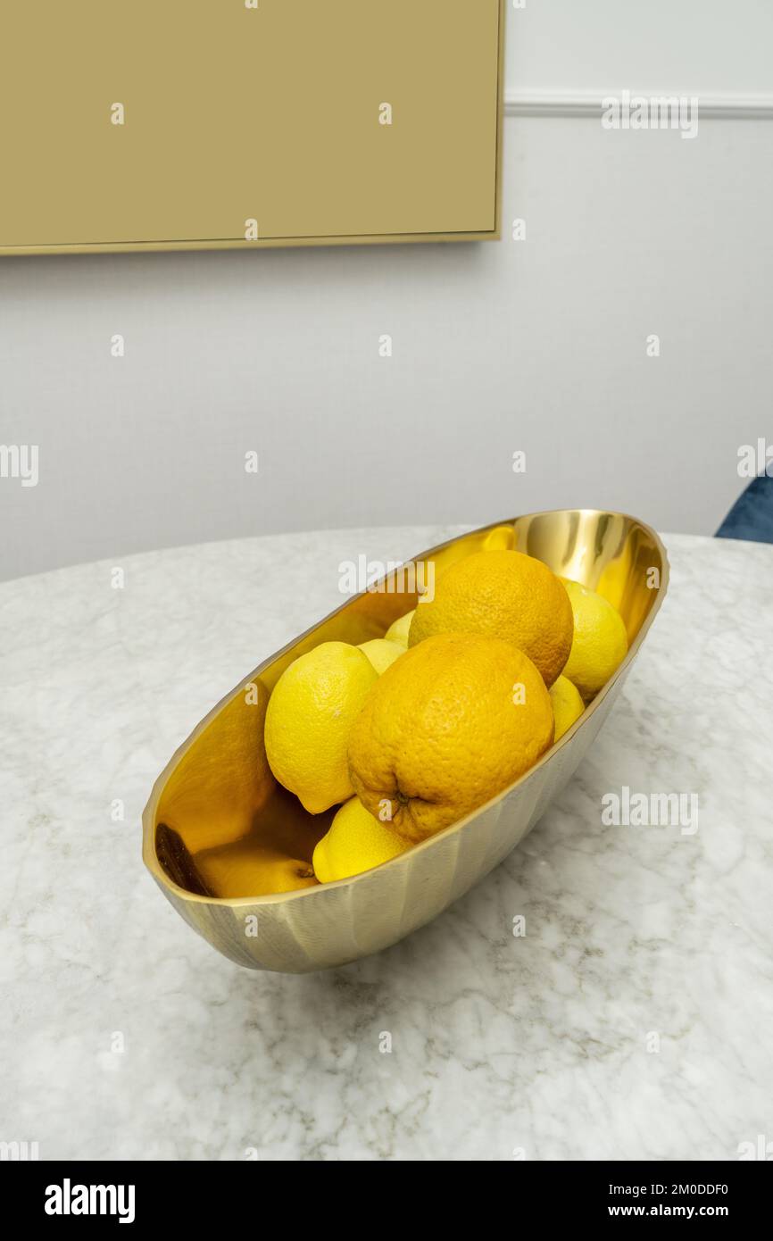 An elongated polished brass centerpiece filled with oranges and lemons Stock Photo