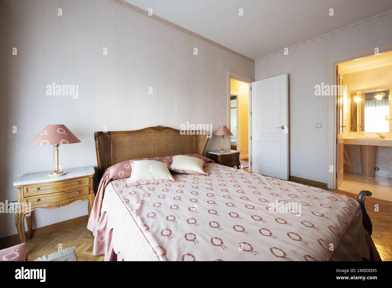 A bedroom with quality antique wooden furniture with a mesh headboard and an en-suite bathroom Stock Photo