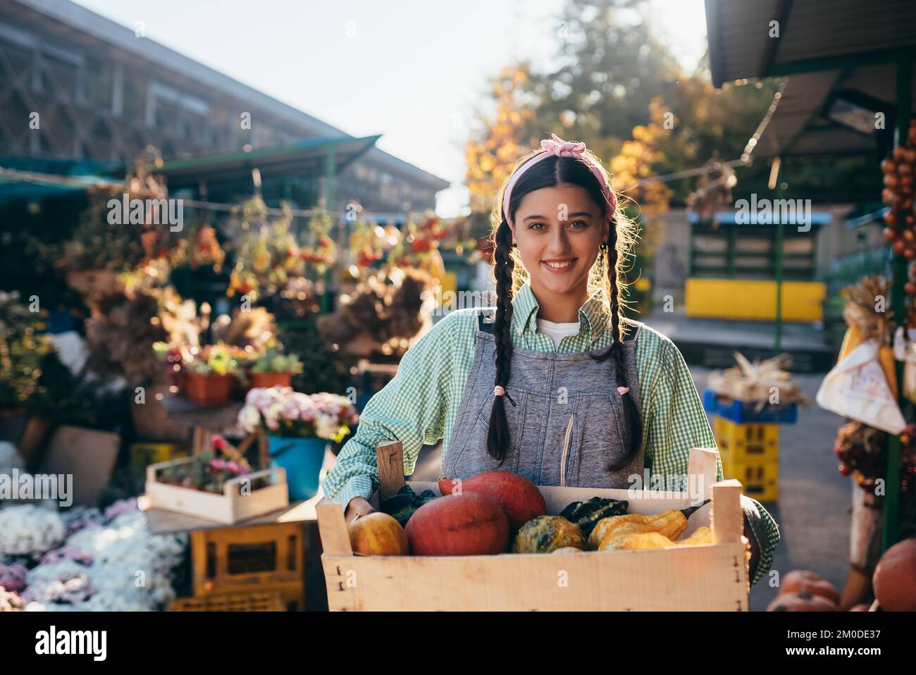 Farmer woman holds a wooden box with pumpkins in hands Stock Photo
