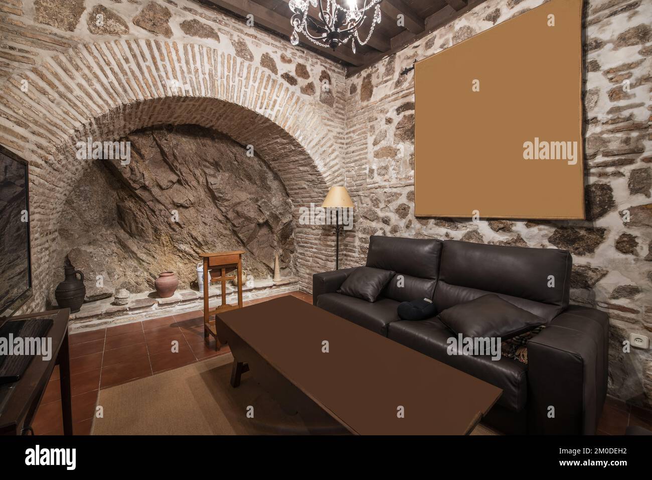 living room of a unique house with stone and brick walls framing a large rock Stock Photo