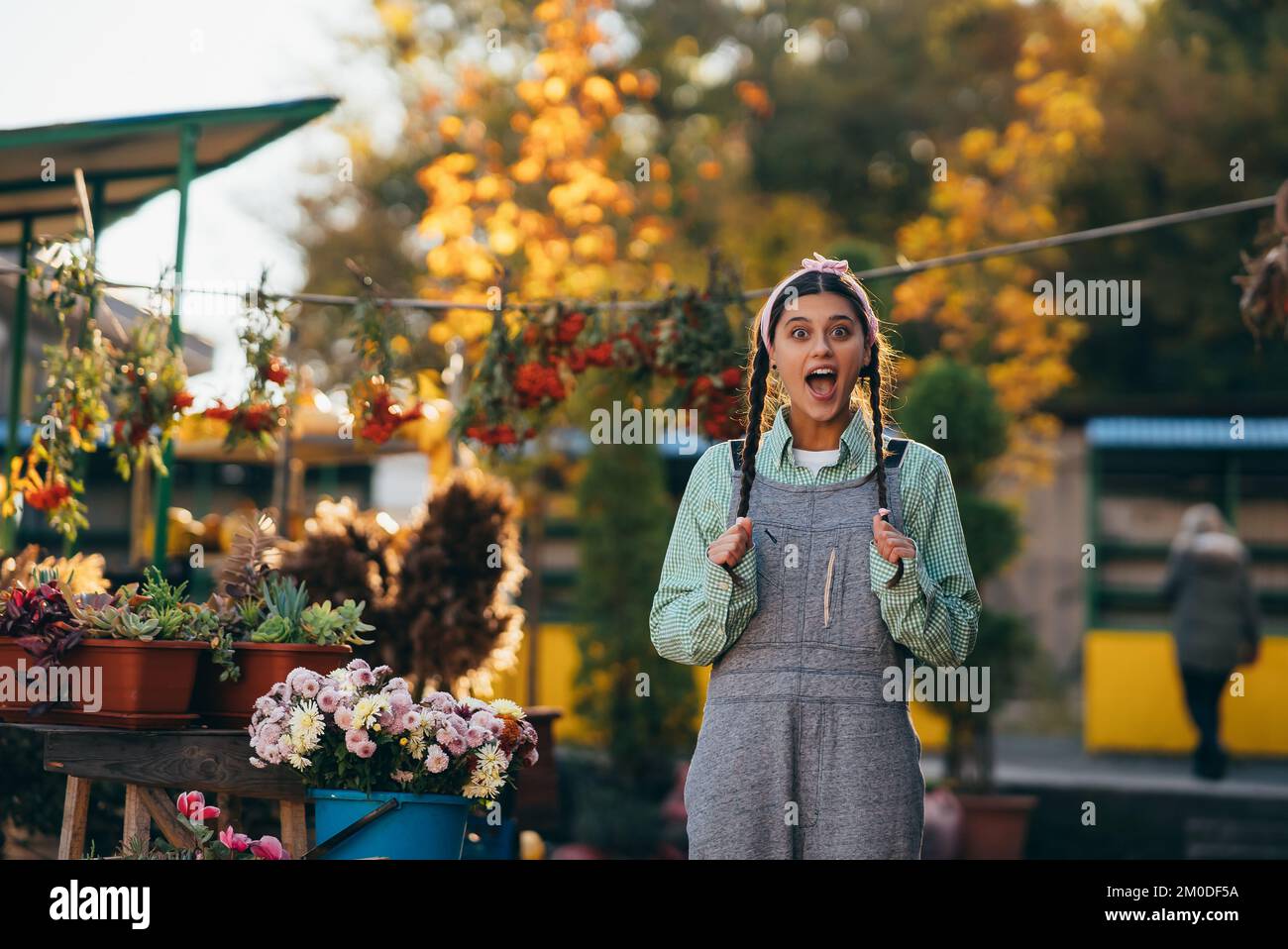 Playful farmer woman in denim overalls smiling sincerely while posing. Stock Photo