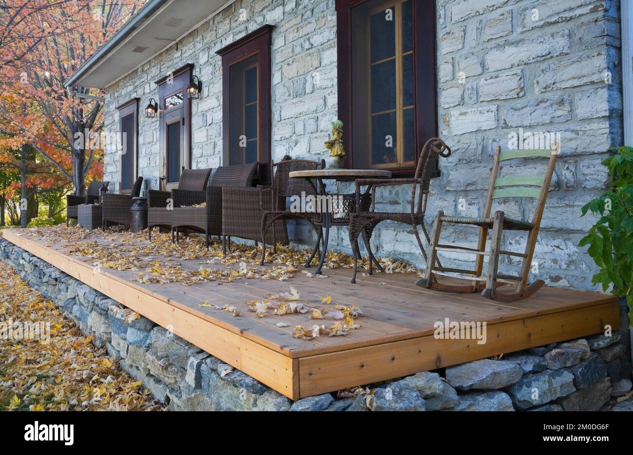 Old circa 1750 Canadiana cottage style fieldstone home facade with wooden veranda in autumn. Stock Photo