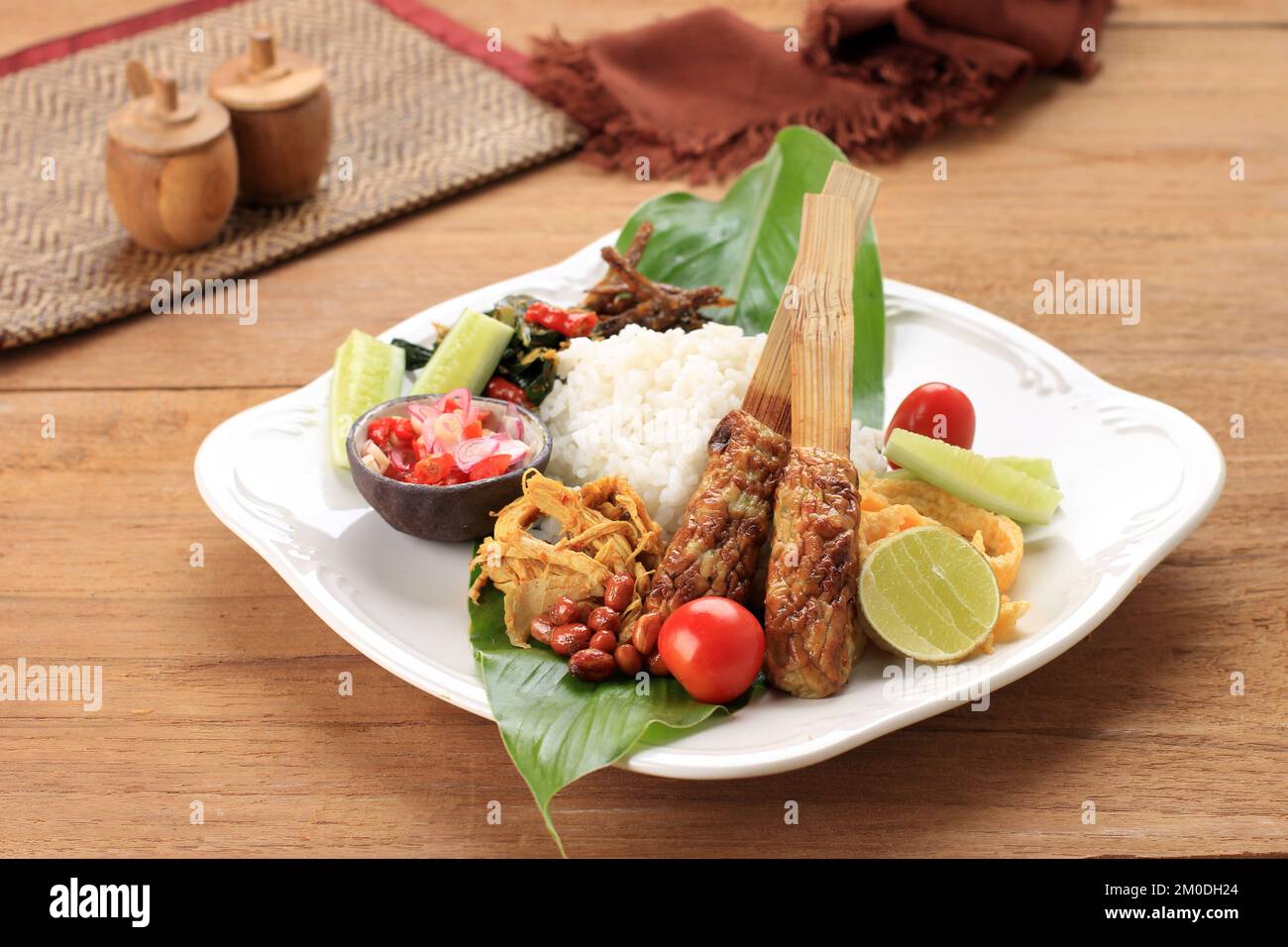 Nasi Campur Bali, Indonesian Balinese Mix Rice with Sate Lilit, Ayam Sisit, Sambal Matah, and Peanut Stock Photo