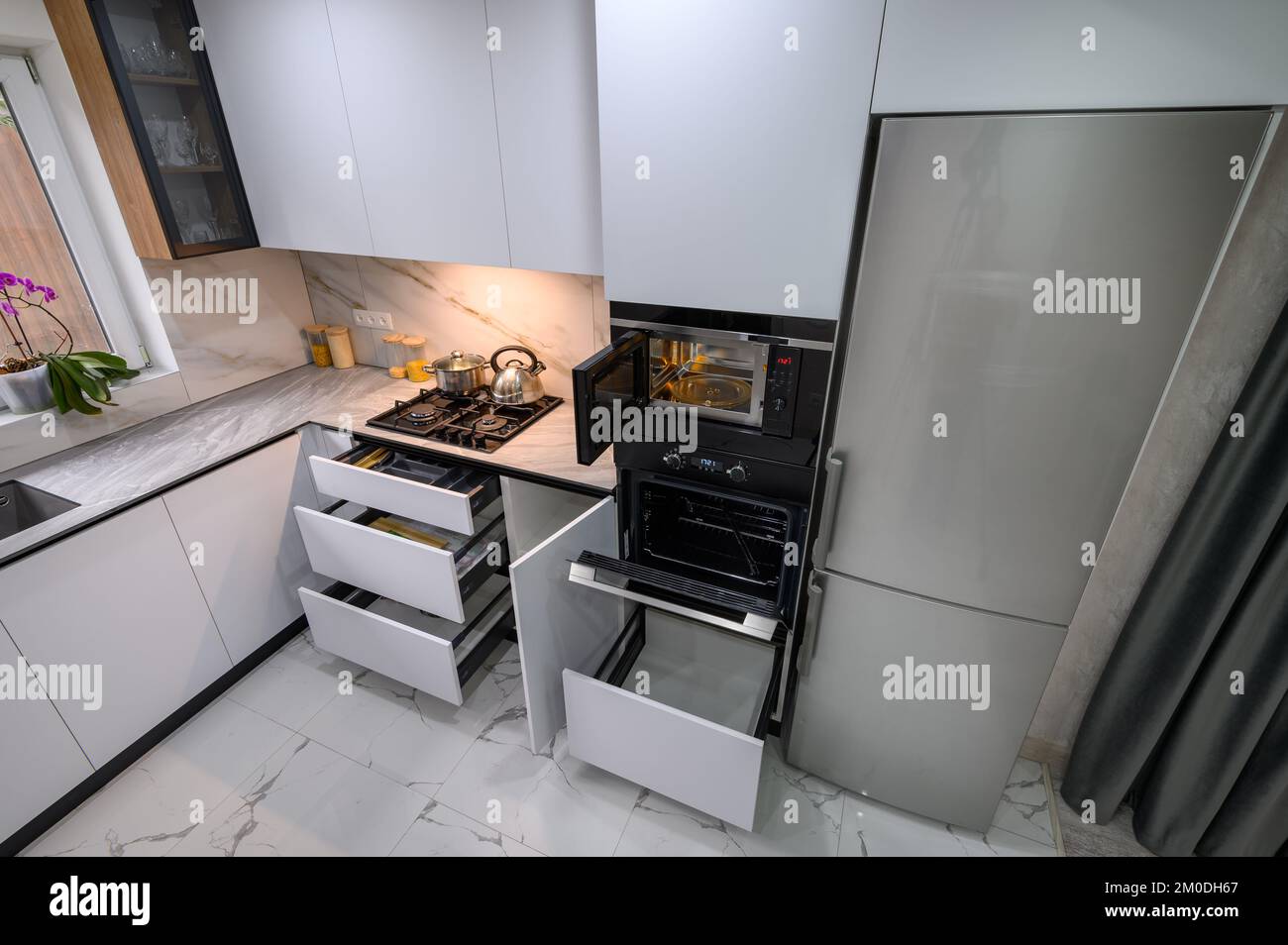 A spacious and updated kitchen with a white color scheme, a marble