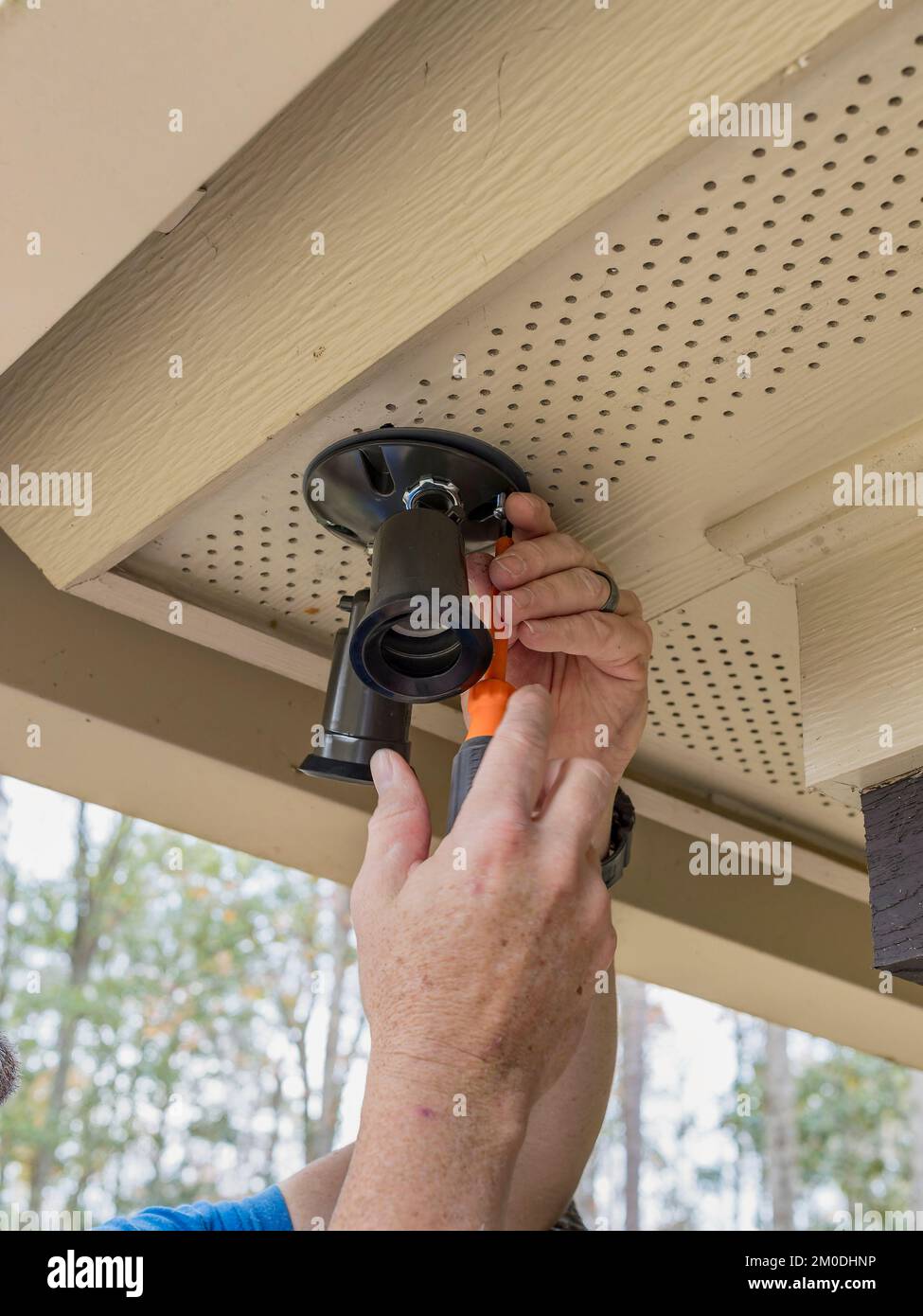 Electrician or handyman at work installing outside security lights or lighting on a residential home for home security. Stock Photo