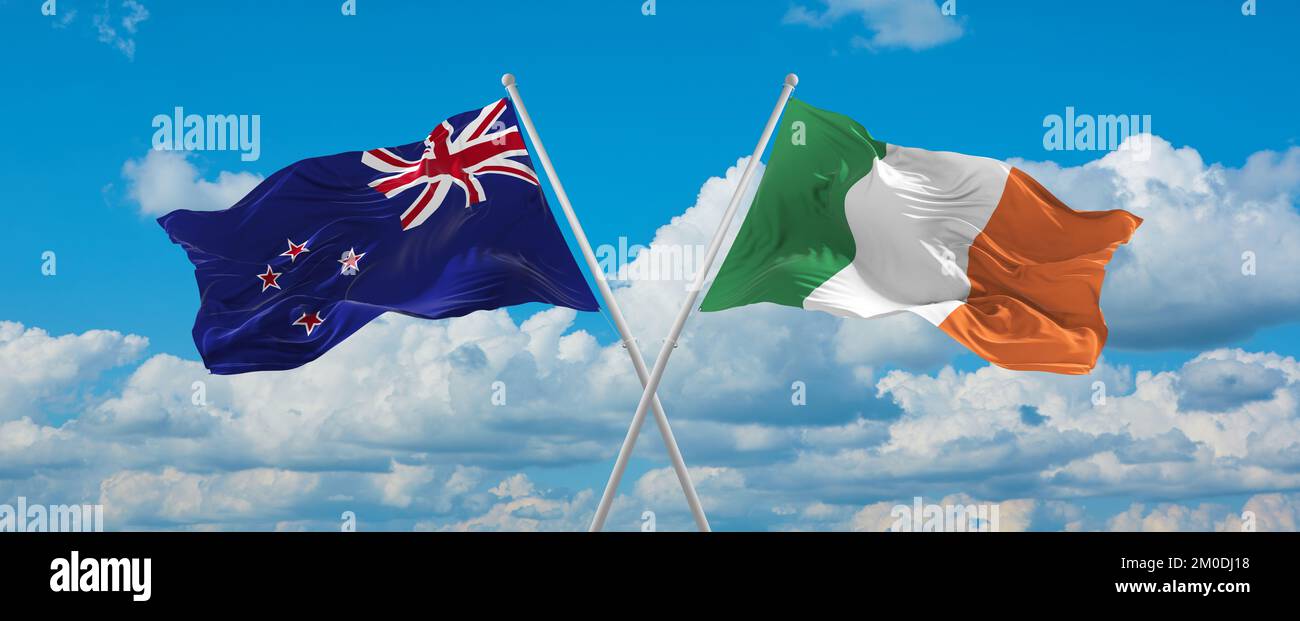 two crossed flags Ireland and New Zeeland waving in wind at cloudy sky ...