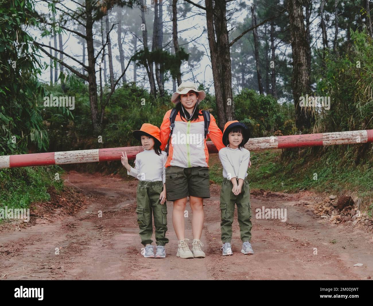 Happy young woman with her daughter walking on a field trip together in the mountains. Family on a hiking adventure through the forest. Parents teach Stock Photo