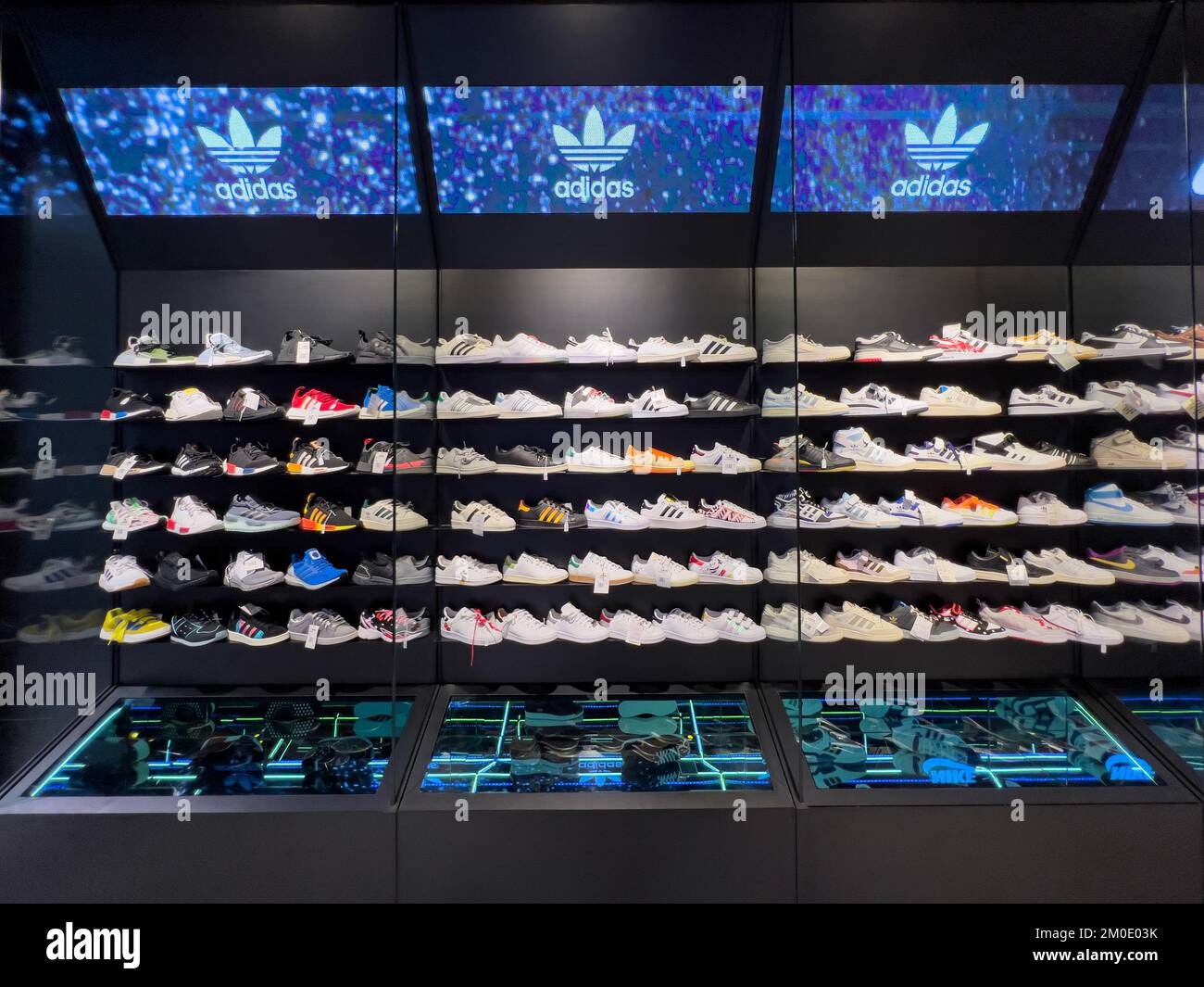 Inside a sneaker shop, shelves displaying Adidas latest shoes models for customers to select. Stock Photo