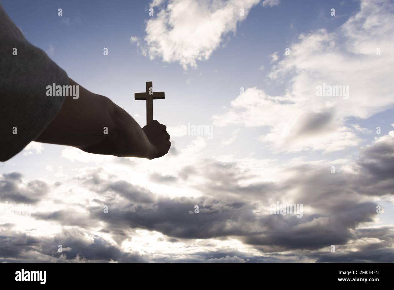 Human hand holding a cross up in the sky. symbol of faith in god Prayer