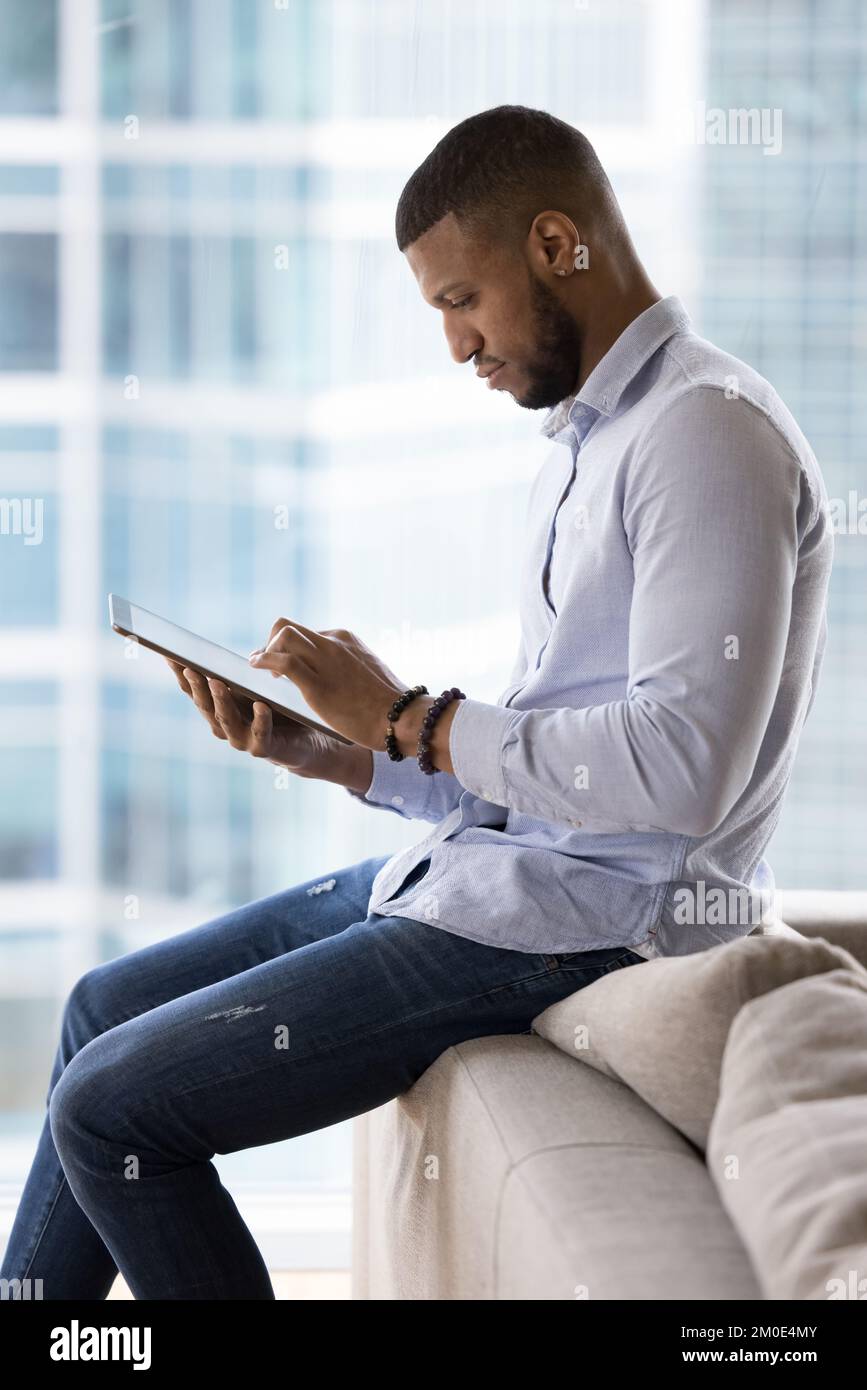 Serious handsome young millennial freelancer man using tablet Stock Photo