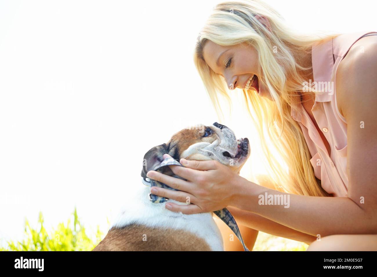 Quality time with my best friend. A smiling blonde woman playing with her dog outdoors. Stock Photo