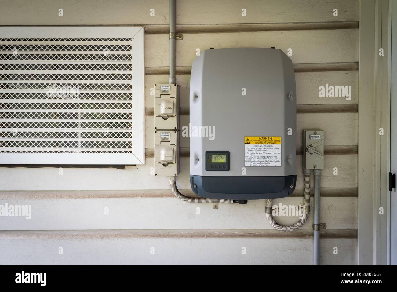 Solar power inverter mounted on side of a house, domestic system Stock Photo