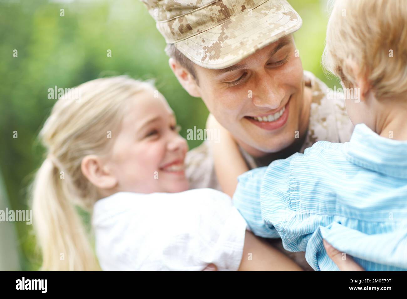 Hes their hero. A returning soldier being welcomed by his two young children. Stock Photo