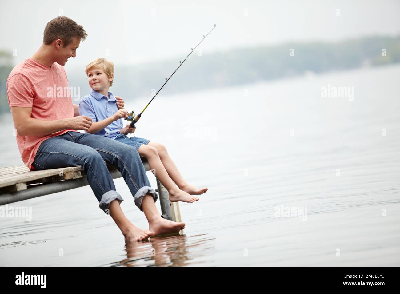 Asian Dad Shows His Son How to Cast a Fishing Rod Gives