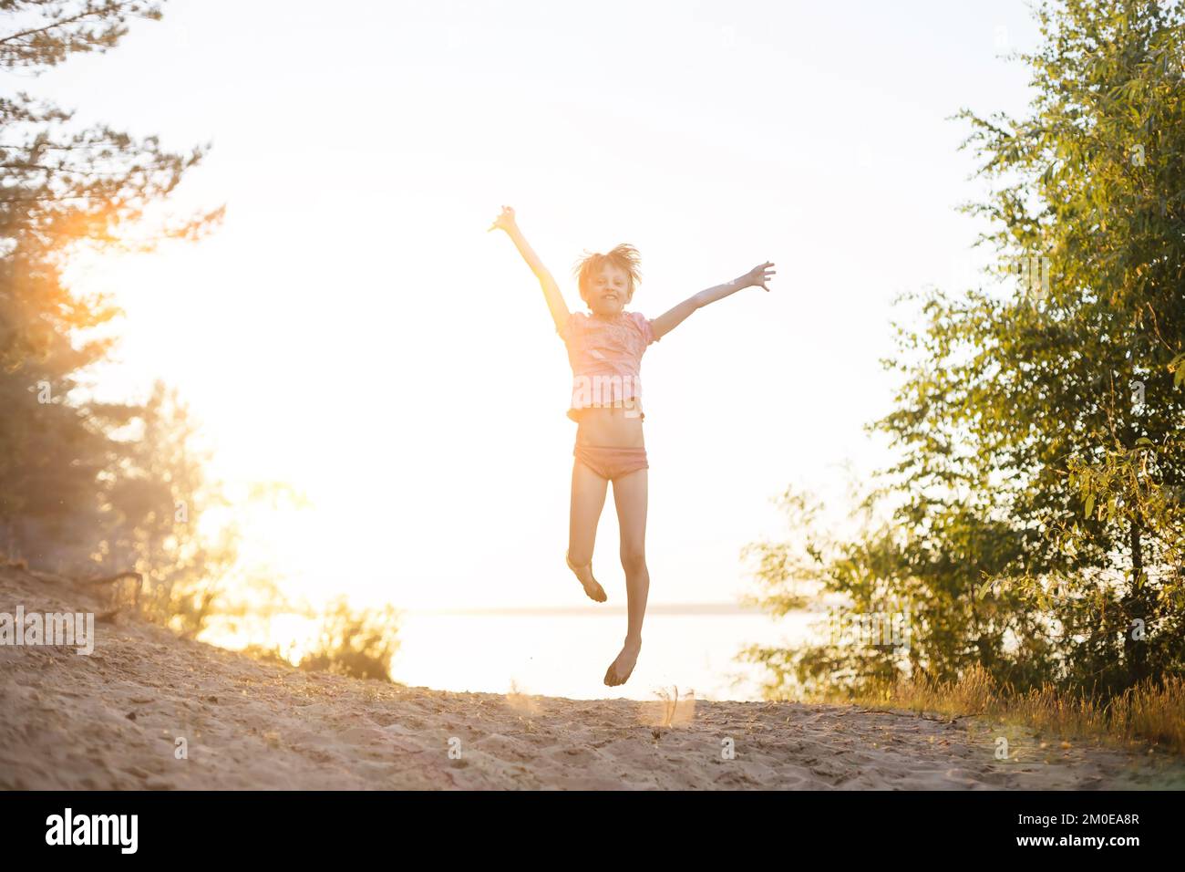 happy little girl jumping on the river bank Stock Photo - Alamy