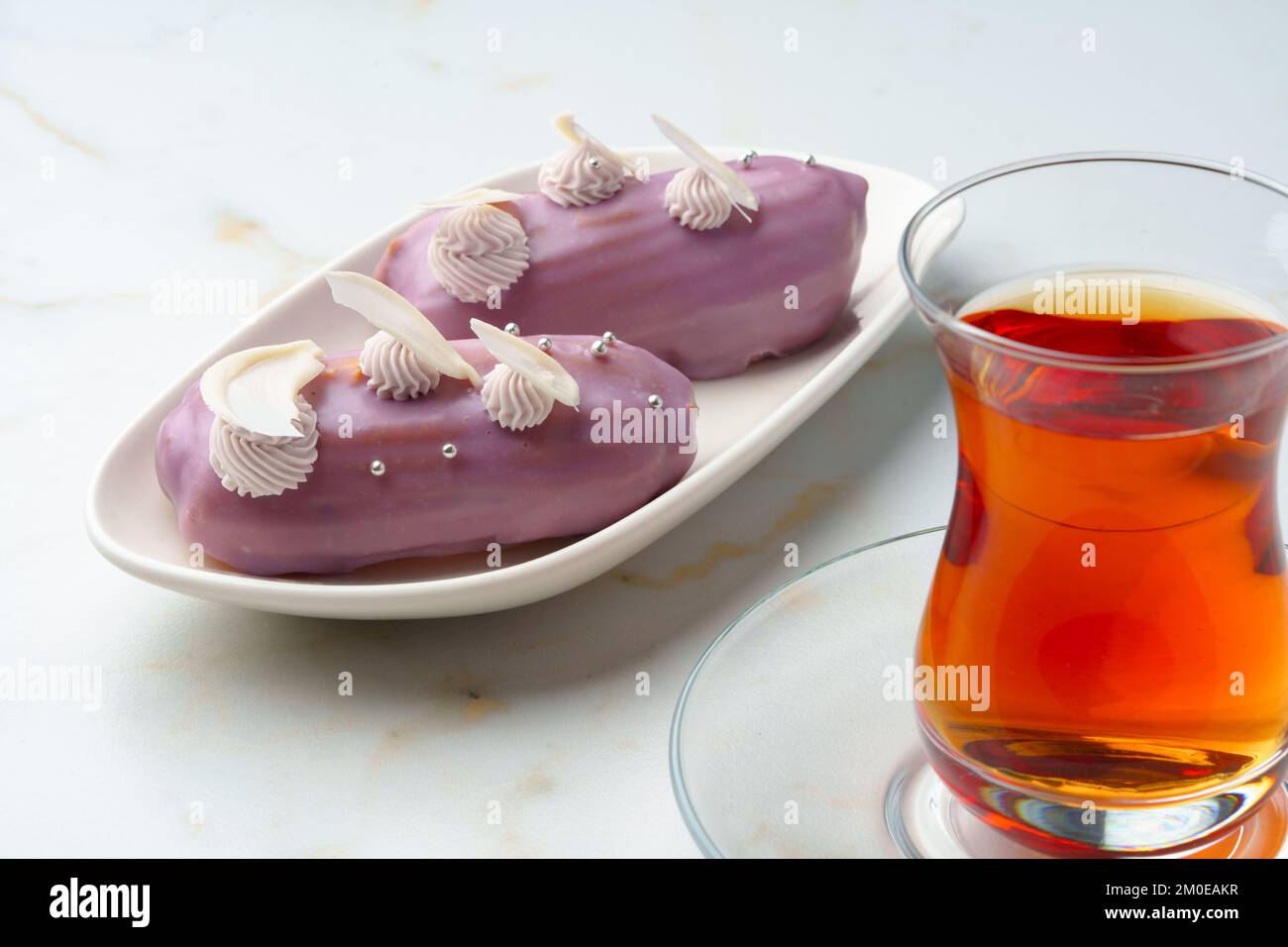 Two eclair cakes with violet frosting on white plate Stock Photo