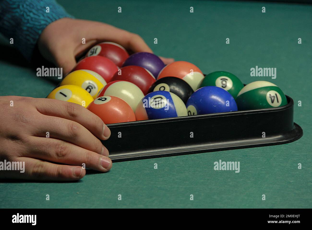A view of hands fixing the position of the billiard balls in the rack