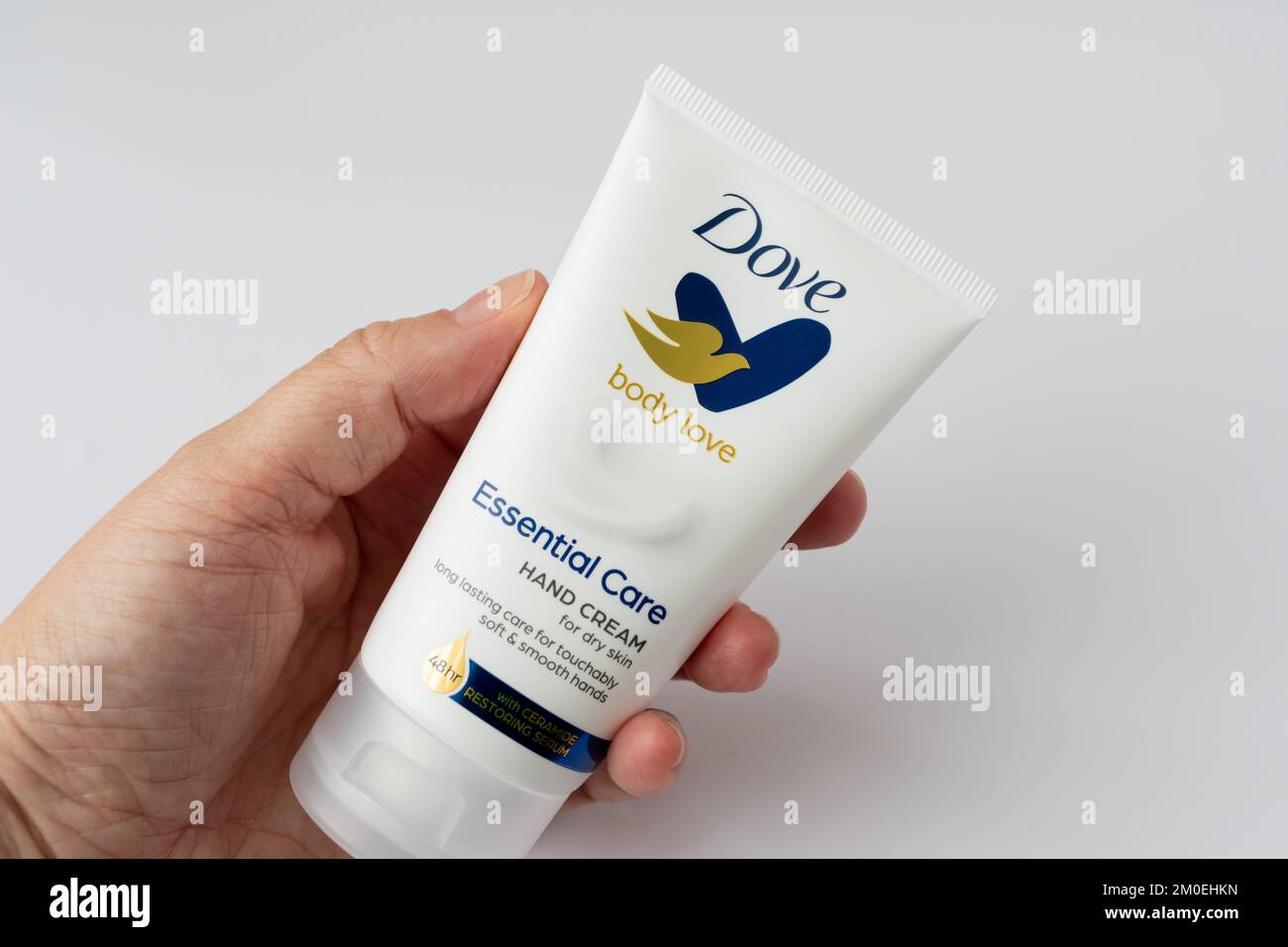 Middle aged female hand holding a tube of Dove moisturising hand cream. Stock Photo