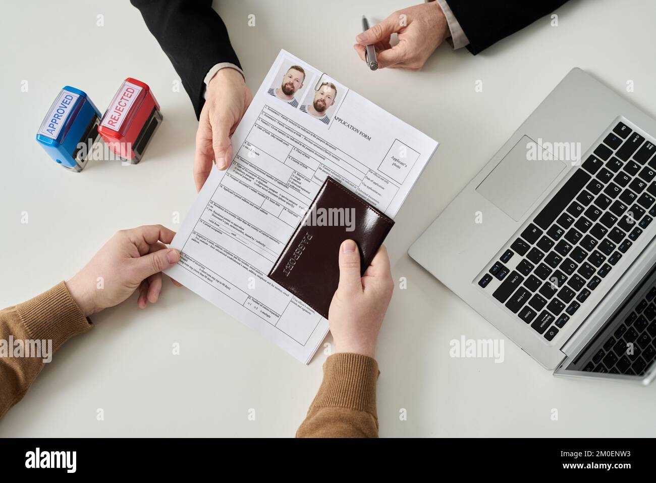 Top view of unrecognizable man applying for visa in immigration office and handing documents to worker Stock Photo
