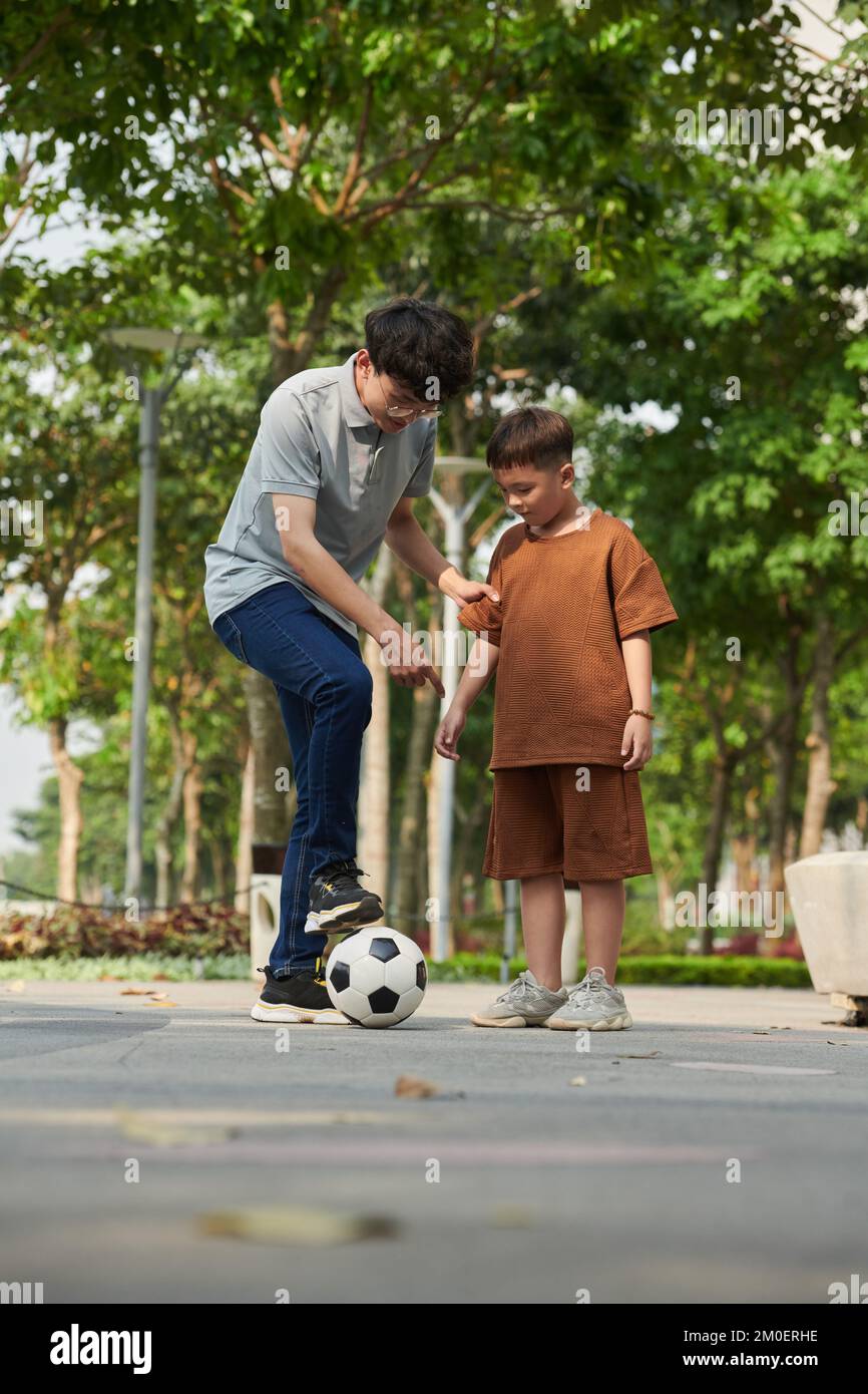 Father explaining son how to kick soccer ball Stock Photo Alamy