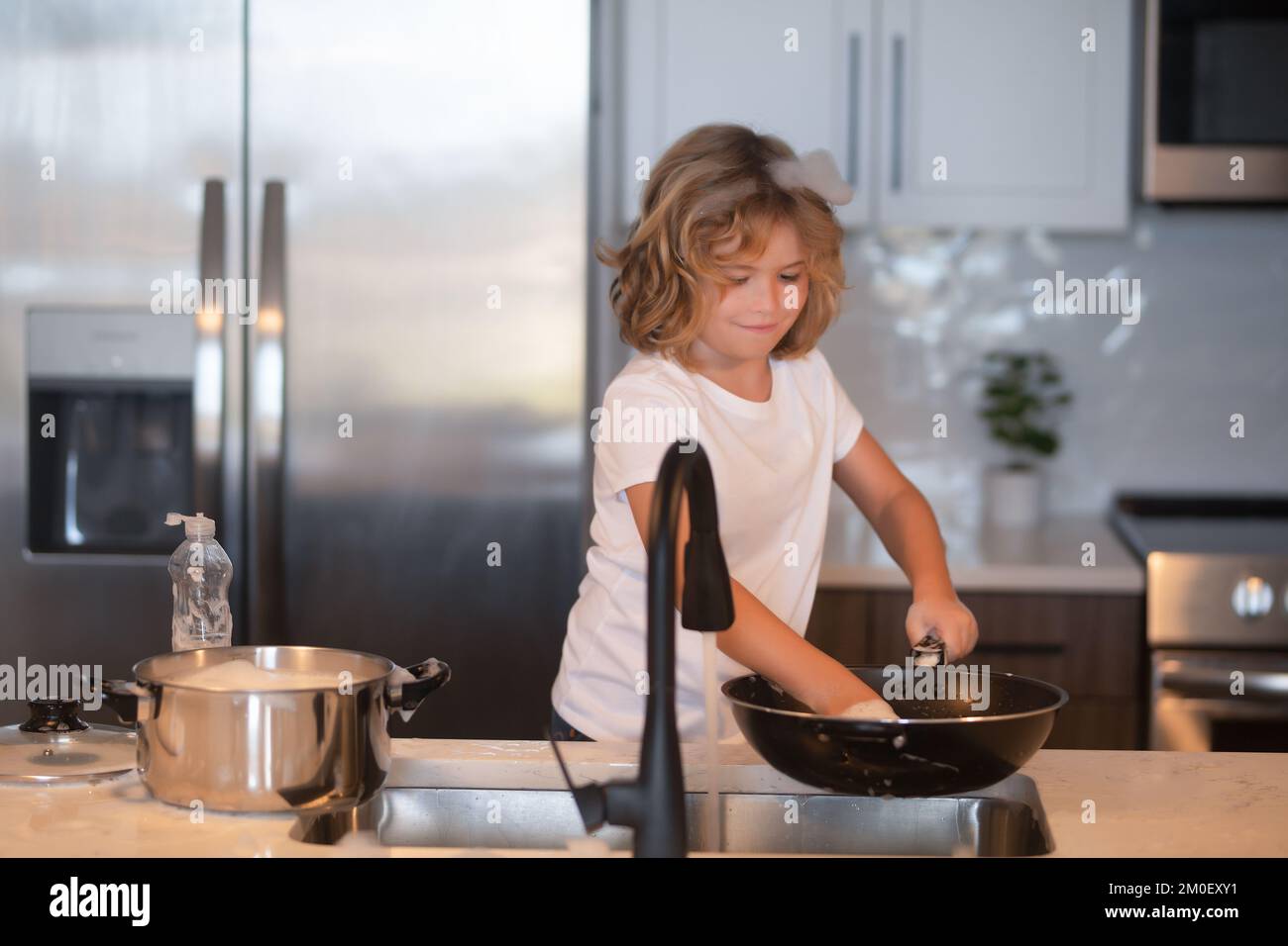 Child cleaning dishes with sponge. Cleaning supplies. Help cleanup