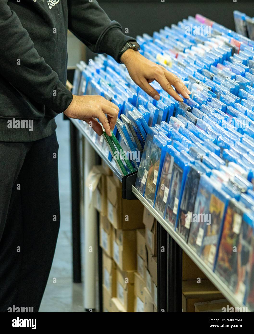 Hands searching and choosing movies and dvds on a shelf in a movie collector's store and merchandising sale of movie discs Stock Photo