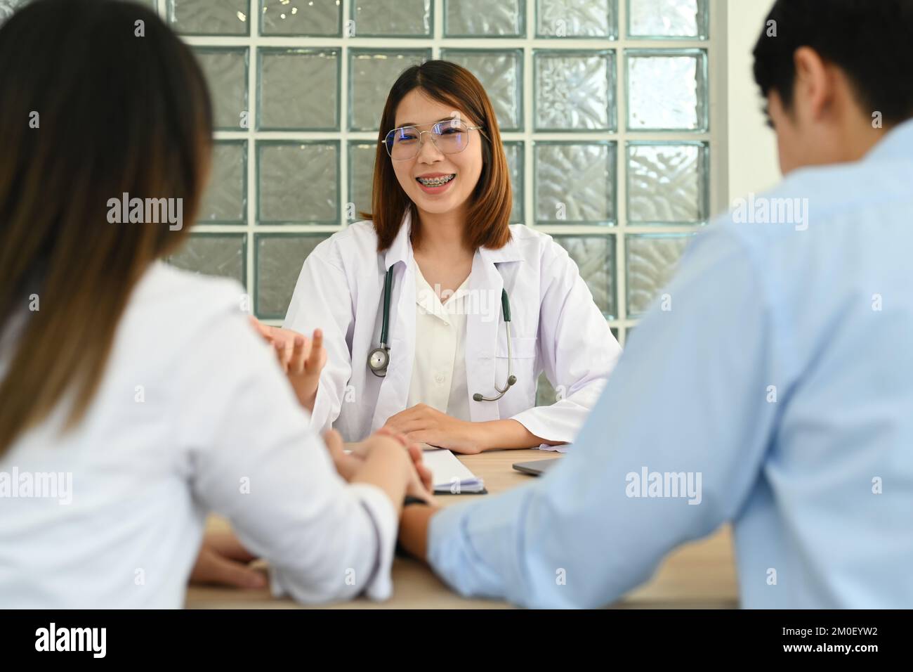 Gynecologist giving advice to married couple during appointment at