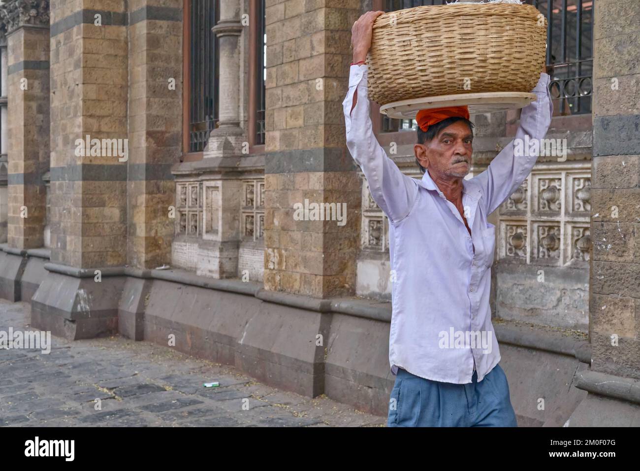 A porter with a basket of fish on his heads, outside Chhatrapati Shivaji Maharaj Terminus (CMST), in Mumbai, India, to forward the basket by train Stock Photo