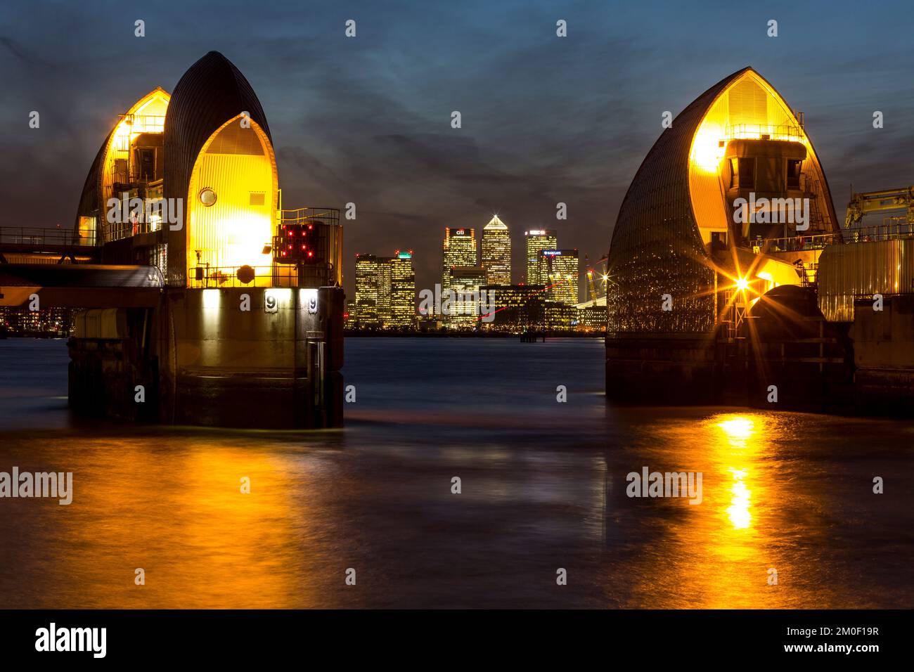The Thames Barrier with Canary Wharf in the evening, London Stock Photo ...