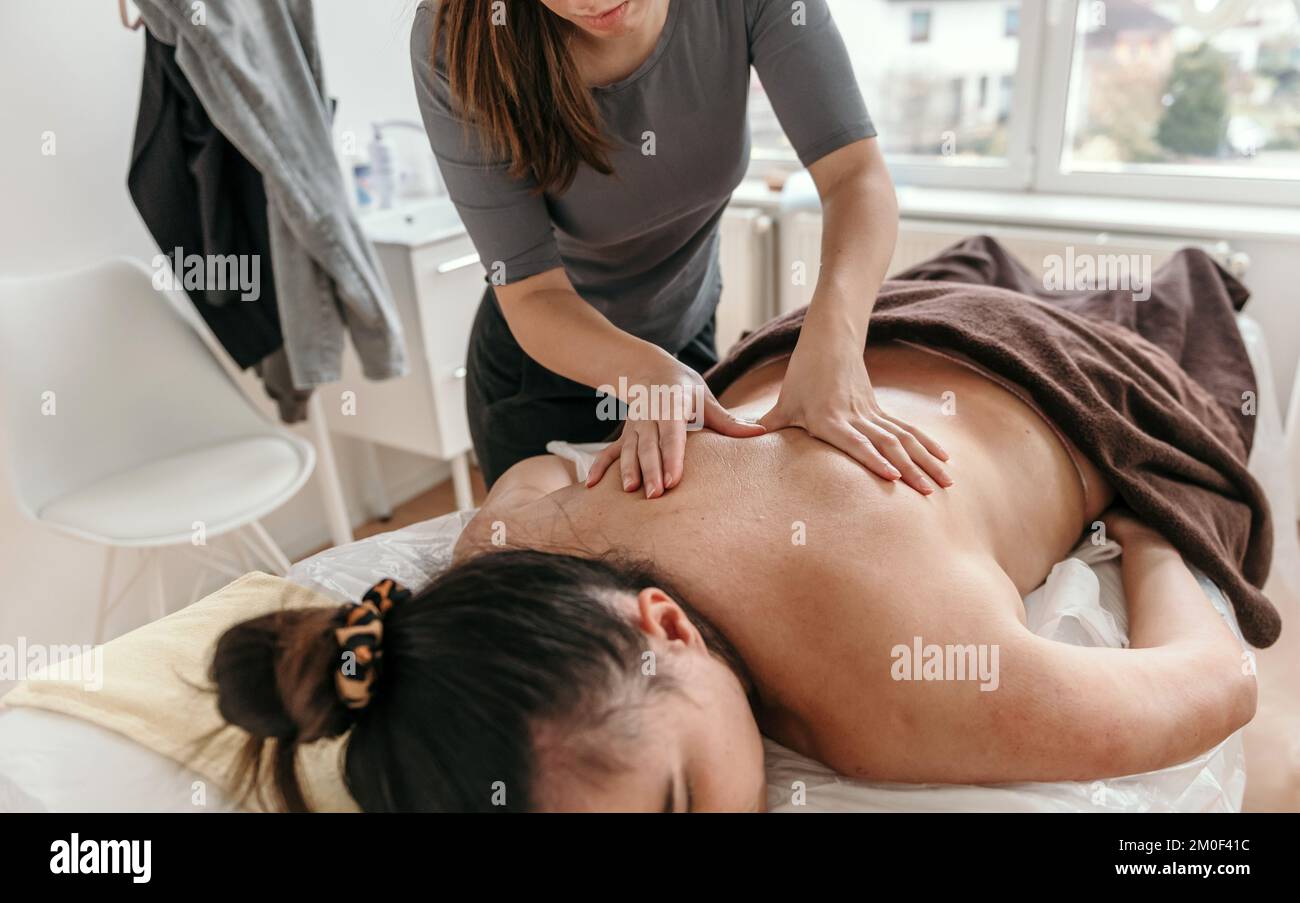 Masseuse doing back massage on young woman on massage table in beauty salon Stock Photo