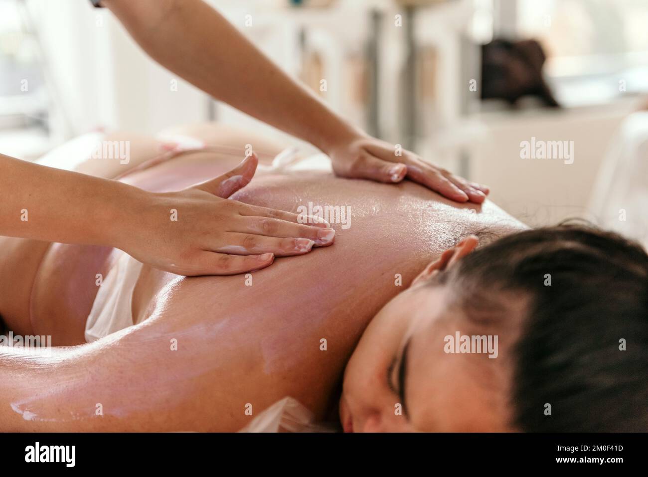 Close-up cropped photo of masseuse doing back massage on young woman on massage table in beauty salon Stock Photo